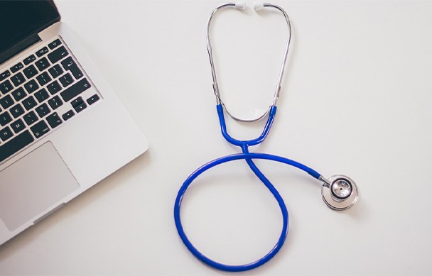 an image with Stethoscope next to laptop on desk 