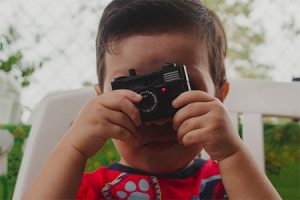 an image with kid holding camera 