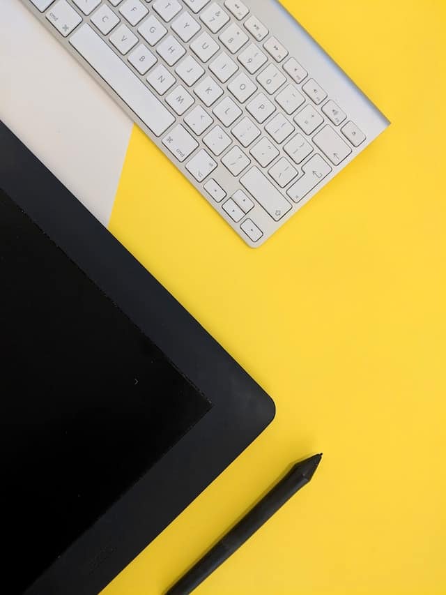 White keyboard beside a tablet and stylus pen